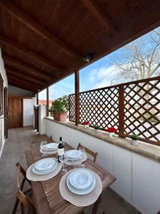 una mesa de madera con platos en el balcón en La Casetta tra Alghero e Stintino, en Palmadula