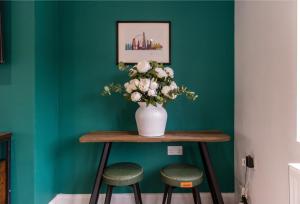 a vase of flowers on a table with two stools at 3 Bedroom Terraced House in Beeston Ideal for Corporate Stays in Beeston