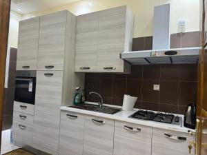 a kitchen with wooden cabinets and a stove at Sall Residence Mbour Saly in Mbour