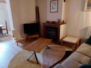 a living room with a couch and a tv at Maison familiale au cœur des Cabannes -montagne, rivière & découvertes in Les Cabannes