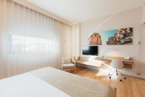 a bedroom with a bed and a desk and a tv at Barceló Valencia in Valencia