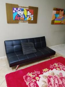 a black couch in a living room with a red rug at Pousada Indi in Ribeirão Preto