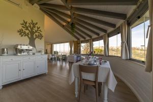 jadalnia z białymi stołami, krzesłami i oknami w obiekcie Villaggio Cristina w mieście Monteodorisio