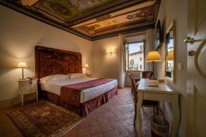 una camera con letto, tavolo e scrivania di Hotel Palazzo San Niccolò & Spa a Radda in Chianti