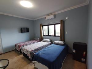 a bedroom with two beds and a window at Pousada Indi in Ribeirão Preto
