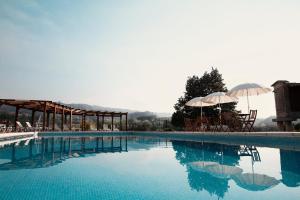 a swimming pool with chairs and umbrellas on top of it at Quinta do Burgo - Nature Hotel in Amares