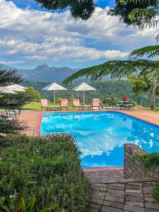 een zwembad met stoelen, tafels en parasols bij Far Hills Country Hotel in George