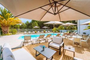 - une piscine avec des chaises, des tables et des parasols dans l'établissement Hôtel Restaurant La Forestière, à Biscarrosse-Plage