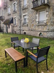 ein Tisch mit zwei Stühlen und ein gelber Krug oben in der Unterkunft Grand Appartement avec Jardin Bretenoux in Bretenoux