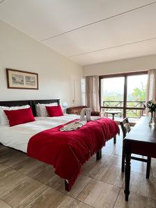 een slaapkamer met een groot bed en een rode deken bij Far Hills Country Hotel in George