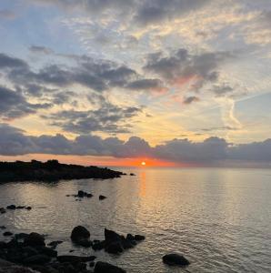 einen Sonnenuntergang über einem Wasserkörper mit Steinen in der Unterkunft Villa Bambi in Budoni