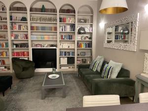 ein Wohnzimmer mit einem Sofa, einem TV und Bücherregalen in der Unterkunft Nel cuore di Bologna in Bologna