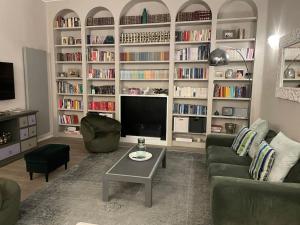 ein Wohnzimmer mit einem Sofa, einem TV und Bücherregalen in der Unterkunft Nel cuore di Bologna in Bologna