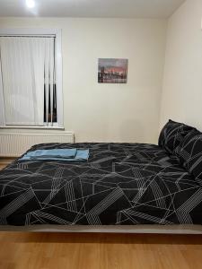 a bedroom with a bed with a black comforter and a window at Nice house near cricket ground in Nottingham