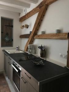 a kitchen with a black counter top and wooden beams at Maison à la Campagne in La Chapelle-dʼAngillon +19 photos