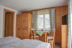 1 dormitorio con cama, mesa y ventana en Gästehaus Familie Gebhard Schädle en Grän