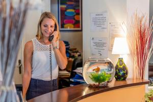 a woman talking on a cell phone next to a fishbowl at Noemys Toulon La Valette - Hotel restaurant avec piscine in La Valette-du-Var