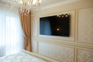 a room with a chandelier and a television on a wall at Boutique Apartments Kempes in Liepāja