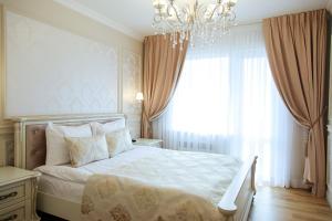 a bedroom with a large bed and a chandelier at Boutique Apartments Kempes in Liepāja