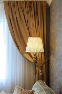 a lamp sitting in front of a curtain next to a bed at Boutique Apartments Kempes in Liepāja +4 photos