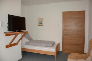 Habitación con cama, TV y puerta. en Gästehaus Familie Gebhard Schädle en Grän