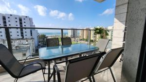 a glass table and chairs on a balcony with a view at Haifa night's in Haifa