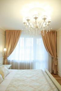 a bedroom with a large bed with a chandelier at Boutique Apartments Siguldas in Liepāja