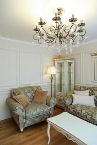 a living room with two couches and a chandelier at Boutique Apartments Siguldas in Liepāja