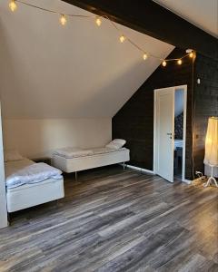 two beds in a room with wood floors and lights at Guesthouse Erlandseröd in Strömstad