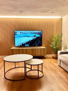 sala de estar con 2 mesas y TV de pantalla plana en Apartamento Home Santo, en Santiago de Compostela