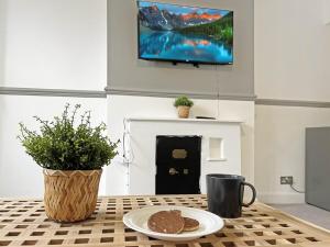 a table with a plate of cookies and a tv on a wall at April Disc - Long Stay - Contractors in Bristol