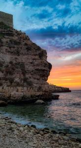 AdelfiaにあるAttico Oasi di Relax Adelfiaの岩の崖の横の海上夕日