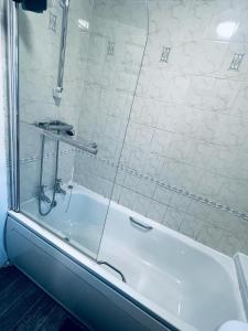 d'une baignoire blanche avec une porte de douche en verre. dans l'établissement Holiday House Near Football Ground, à Nottingham