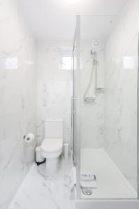 a white bathroom with a toilet and a shower at Budget City Center Apartment Aldgate - Tower Bridge in London