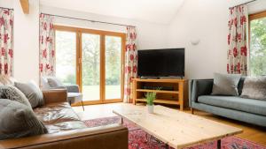 uma sala de estar com um sofá e uma televisão em Oak Tree Farm em Buxton