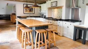 a kitchen with a wooden island with bar stools at Oak Tree Farm in Buxton