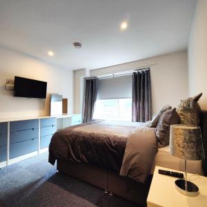 a bedroom with a bed with a television and a window at Liverpool Stays - Kempston Court in Liverpool