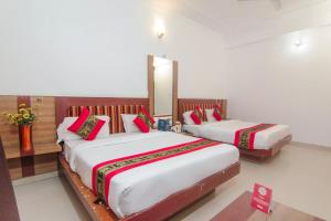 um quarto com 2 camas e almofadas vermelhas em OYO Hotel Indiana Near Gomti Riverfront Park em Vibhuti Khand
