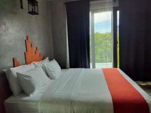 a bedroom with a large bed with a window at Cicada Hotel Kanchanaburi in Kanchanaburi City