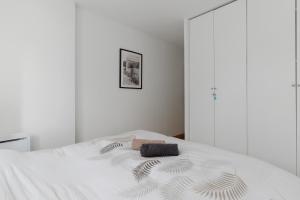 Un dormitorio con una cama blanca con una toalla. en Magnificent 8P2BR apartment with indoor pool and garden - Deauville, en Deauville