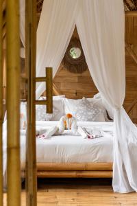 uma cama com dois bichos de peluche em cima em Bamboo House - Ecobreeze em Sidemen