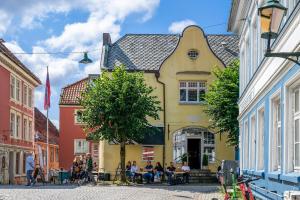 eine Gruppe von Personen, die vor einem gelben Gebäude an Tischen sitzen in der Unterkunft Cozy, Self-Check In, 5 Guests in Bergen