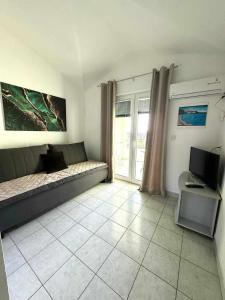 ein Wohnzimmer mit einem Sofa und einem Schreibtisch mit einem Computer in der Unterkunft Apartments Natalika in Podaca