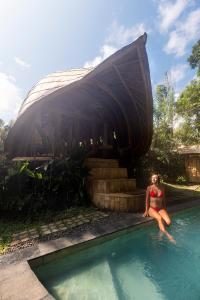 una mujer sentada en una piscina con un barco en Bamboo House - Ecobreeze, en Sidemen