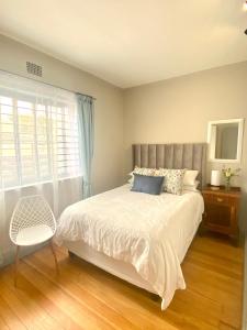 a bedroom with a bed and a chair and a window at Stay on Main in Paarl