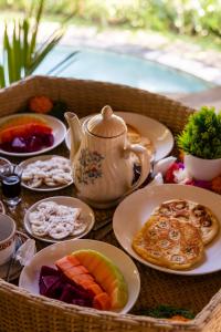 einen Tisch mit Teller mit Speisen und einer Teekanne in der Unterkunft Bamboo House - Ecobreeze in Sidemen