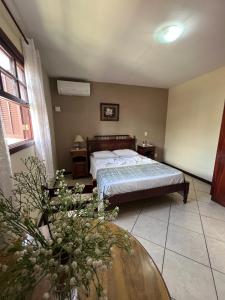 a bedroom with a bed and a table with flowers at Pousada Finlândia in Penedo