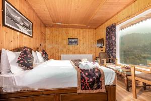 a bedroom with a bed and a desk and a window at Marina Drung Waterfall By Stay Pattern in Gulmarg