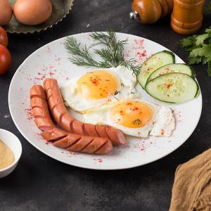 a plate of eggs and sausage and cucumbers on a table at Quba ALFA-M Motel in Quba