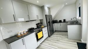 uma grande cozinha com armários brancos e pisos de madeira em Perfect Contractor Stay House I Sleeps 7 People I 20 Percent Off xx LIMITED OFFER xx em Borehamwood